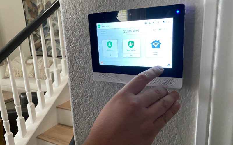 A man is setting an alarm on a smart home panel in his home
